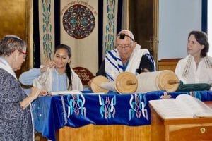 Girl blessing the Torah surround by two women and a man