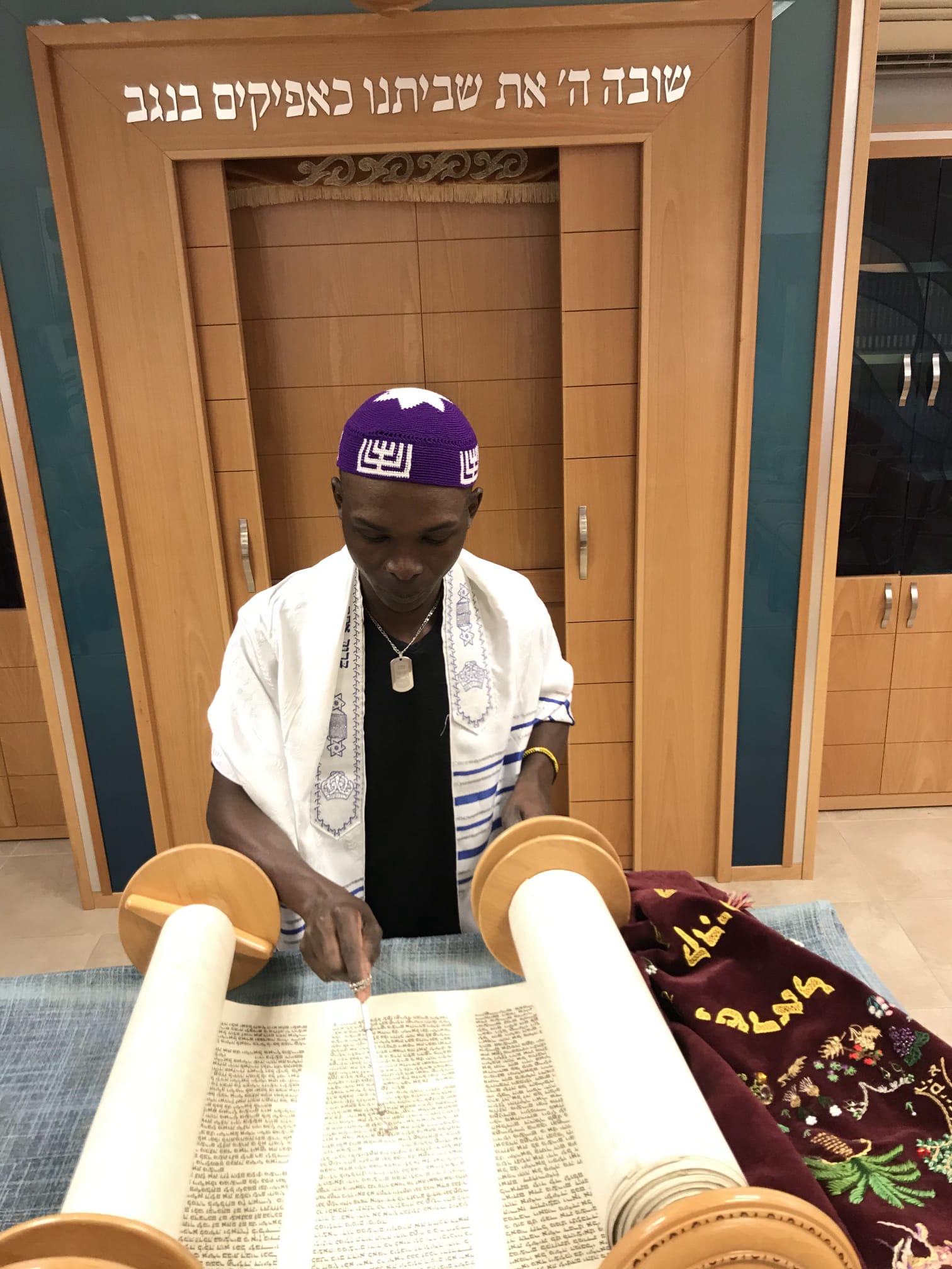 Yosef Kibita reading from a Torah scroll